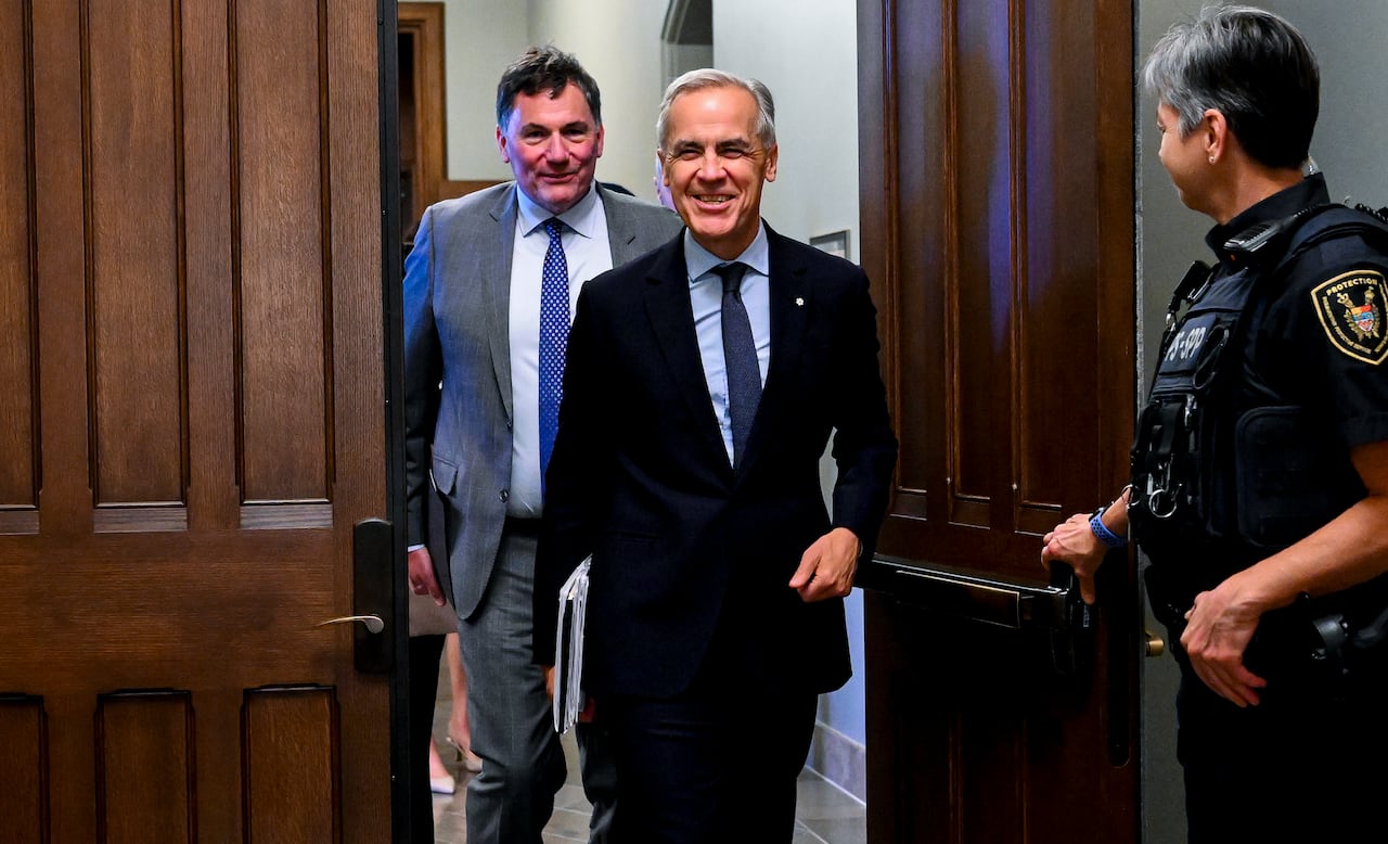 Image 6: Mark Carney walks past a door held open by a parliamentary protective service officer, with Dominic LeBlanc walking behind him.